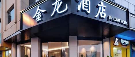 Um hotel com fachada moderna, entrada destacada e placa indicando ser o Jin Long Hotel.