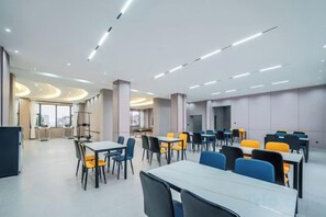 A modern dining area with tables and chairs, a large window, and a view of the city. - Golden Dragon Hotel (Red River Maitreya Branch) (Mile)