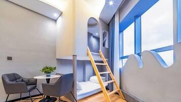 A modern room with a bunk bed, a small table with a plant, and a ladder.