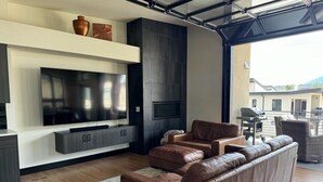 Ein modernes Wohnzimmer mit einem großen Flachbildfernseher, einem Ecksofa und einem Kamin.
