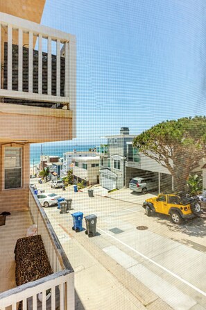 Un quartier résidentiel avec des immeubles modernes, une rue bordée de voitures garées et une vue dégagée sur l’océan.