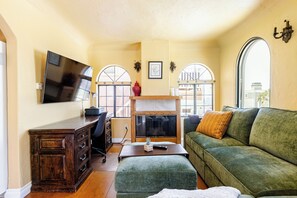 A living room with a television, a fireplace, a sofa, and a desk.