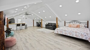 A spacious loft bedroom with a large bed, a desk, and a kitchenette.