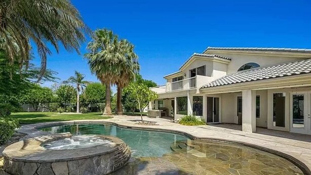 Et hus med swimmingpool, jacuzzi og en velplejet have.