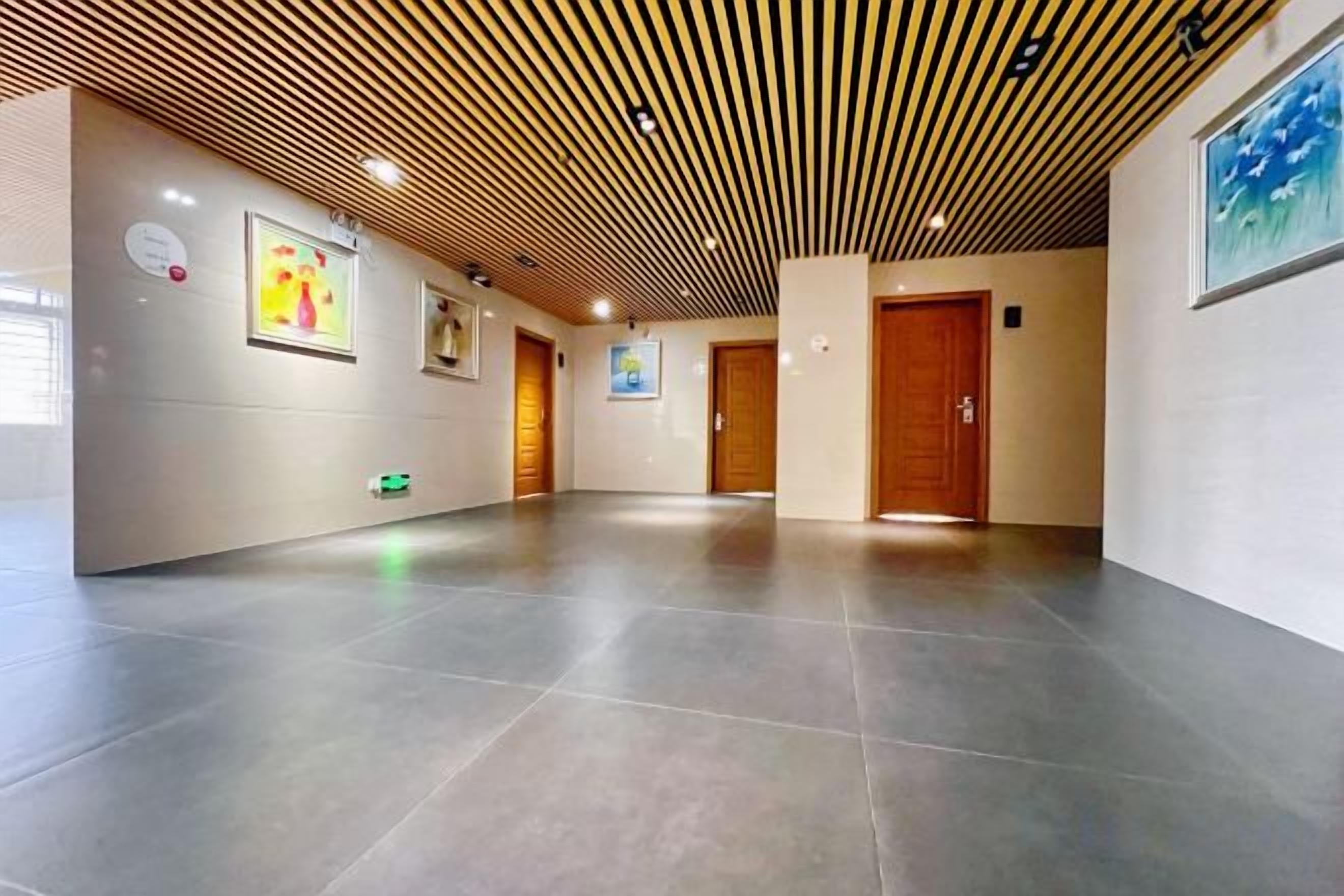 A hallway with a wooden ceiling, tiled floor, and doors leading to rooms.