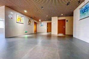 A hallway with a wooden ceiling, tiled floor, and doors leading to rooms. - HaoJiang Hotel (Huizhou)