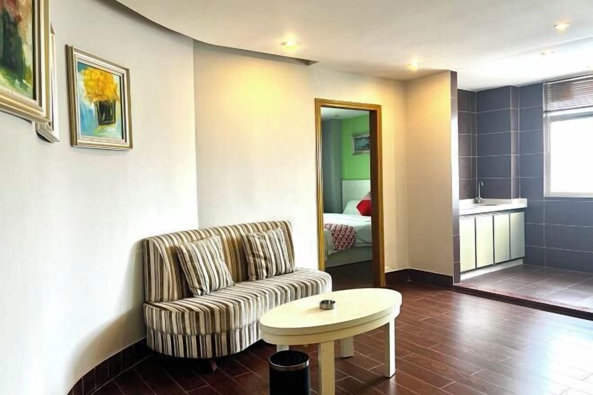 A modern living room with a striped sofa, a round table, and a small trash bin.