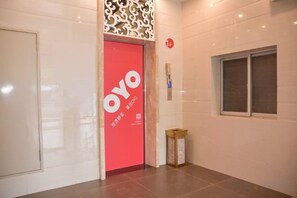 A hallway with a red door labeled 'OYO' and a small window on the right. - HaoJiang Hotel (Huizhou)