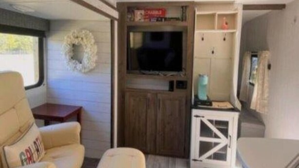 Ein kompaktes Wohnmobil-Interieur mit einer Sitzecke, Hocker und einem kleinen Tisch.