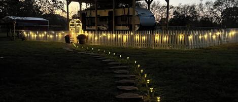 A pathway lined with lanterns leading to a gazebo.