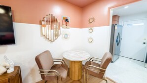 Una habitación moderna con una mesa redonda, dos sillas, un televisor y decoración en la pared.