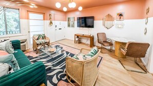 Una sala de estar con un sofá, sillas, una mesa de centro, un televisor y decoración en las paredes.