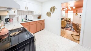 Una cocina moderna con armarios blancos, una estufa negra y un hervidor rosa.