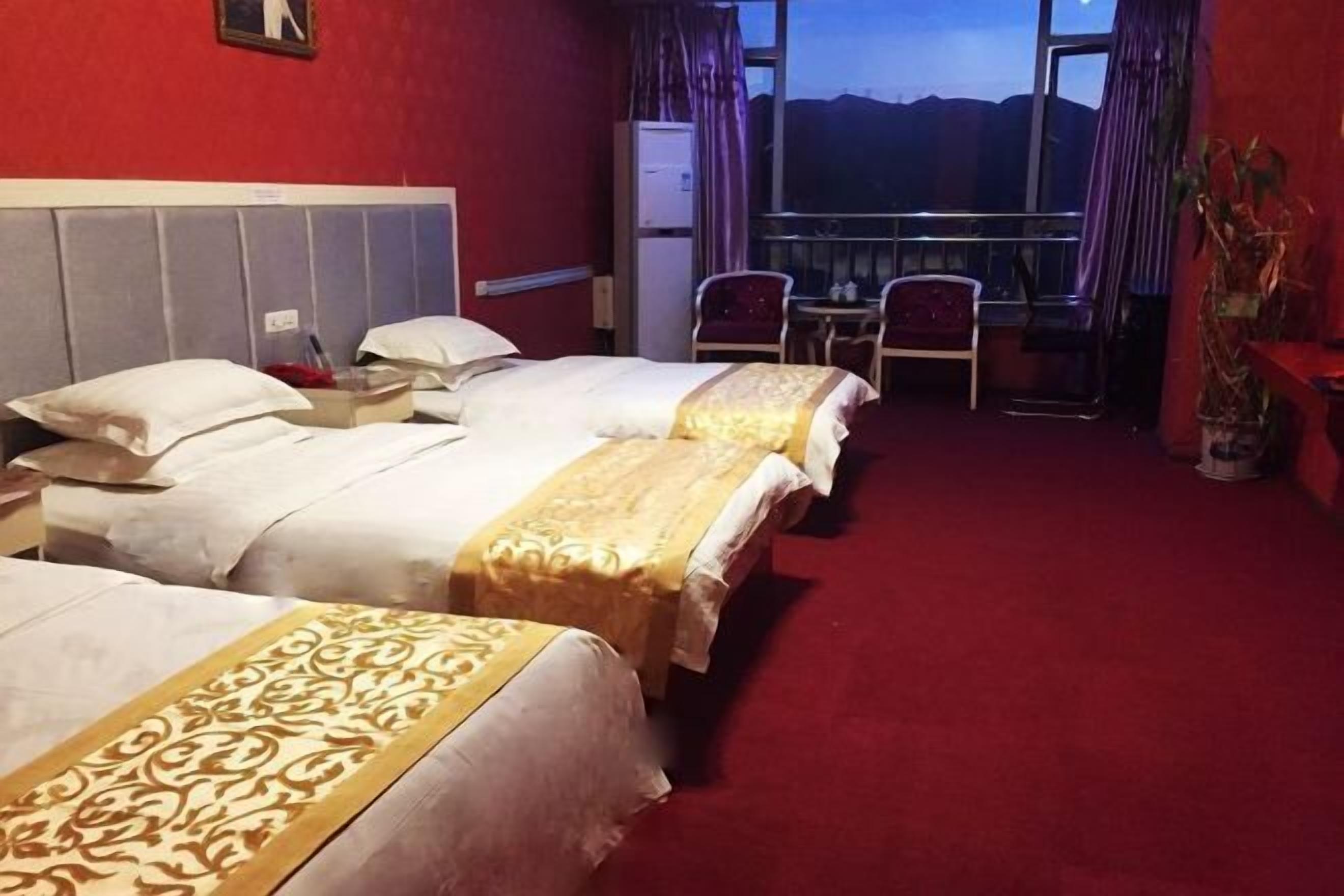 Et hotelværelse med to senge, et lille bord, en stol og en balkon med udsigt.