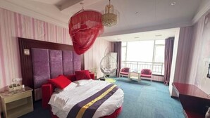 Une chambre d’hôtel avec un grand lit, une table de chevet, une chaise, un fauteuil suspendu et un balcon avec vue.