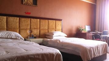 A hotel room with two beds, a desk with a computer, and a chair.