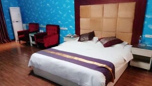 Une chambre d’hôtel avec un grand lit, une chaise rouge, une petite table et une armoire blanche.
