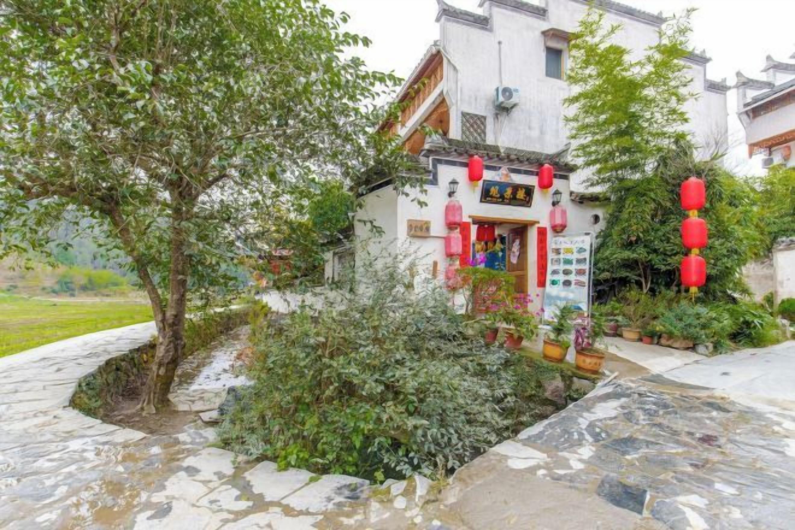Edificio tradicional con un letrero, rodeado de follaje y senderos de piedra.