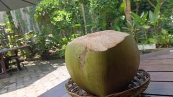 Un coco grande sobre una cesta de mimbre en una mesa de madera.