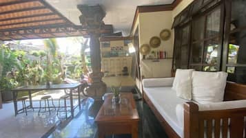 Una habitación con un sofá de madera, una mesa de comedor y un piso de baldosas.