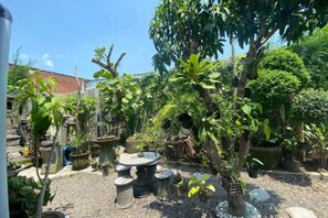 Un jardin agrémenté de différentes plantes en pot et d’une table en pierre.