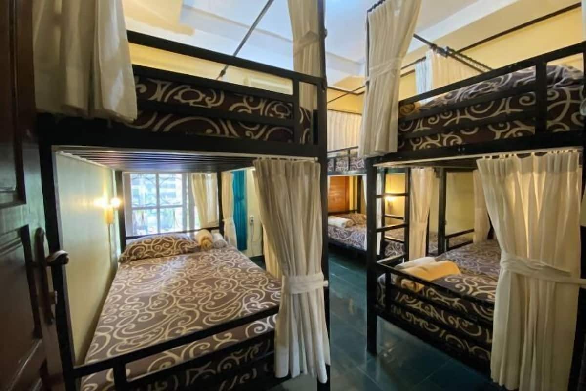 Une chambre avec des lits superposés, chacun étant agrémenté d’une couvre-lit à motifs et de rideaux blancs.