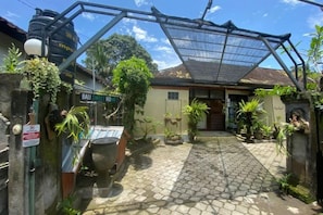 Een binnentuin met een huis, een waterreservoir en een metalen hek.