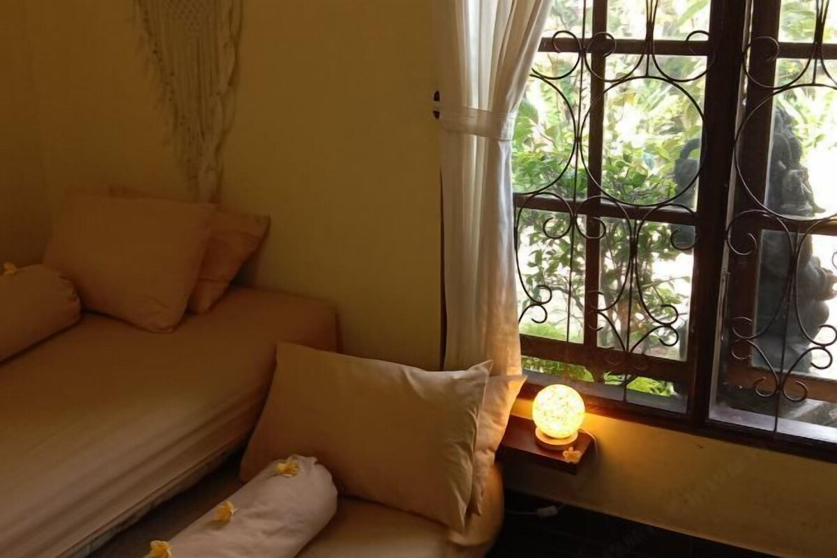 Une chambre avec un lit, une fenêtre ornée de barreaux en fer décoratifs et une lampe de chevet.