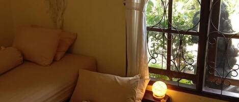A room with a bed, a window with decorative iron bars, and a bedside lamp.