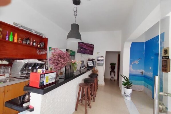 A kitchen with a bar area, a coffee machine, and a hanging light fixture. - Hola Inn (Shenzhen)