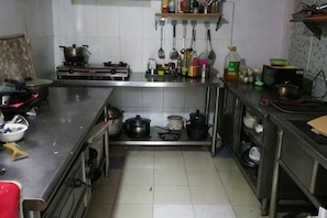 A kitchen with stainless steel appliances, a stove, pots, and a variety of utensils. - Hola Inn (Shenzhen)