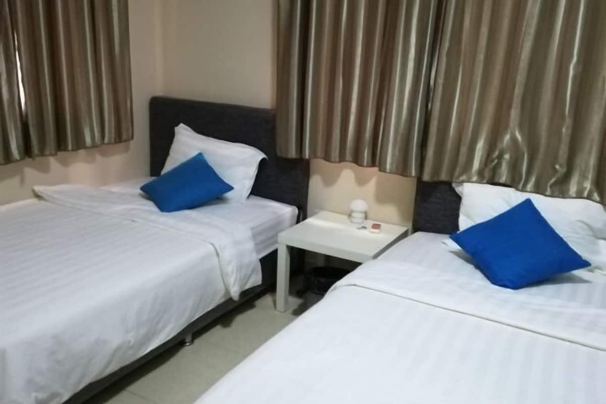 A hotel room with two beds, a small table, and curtains.