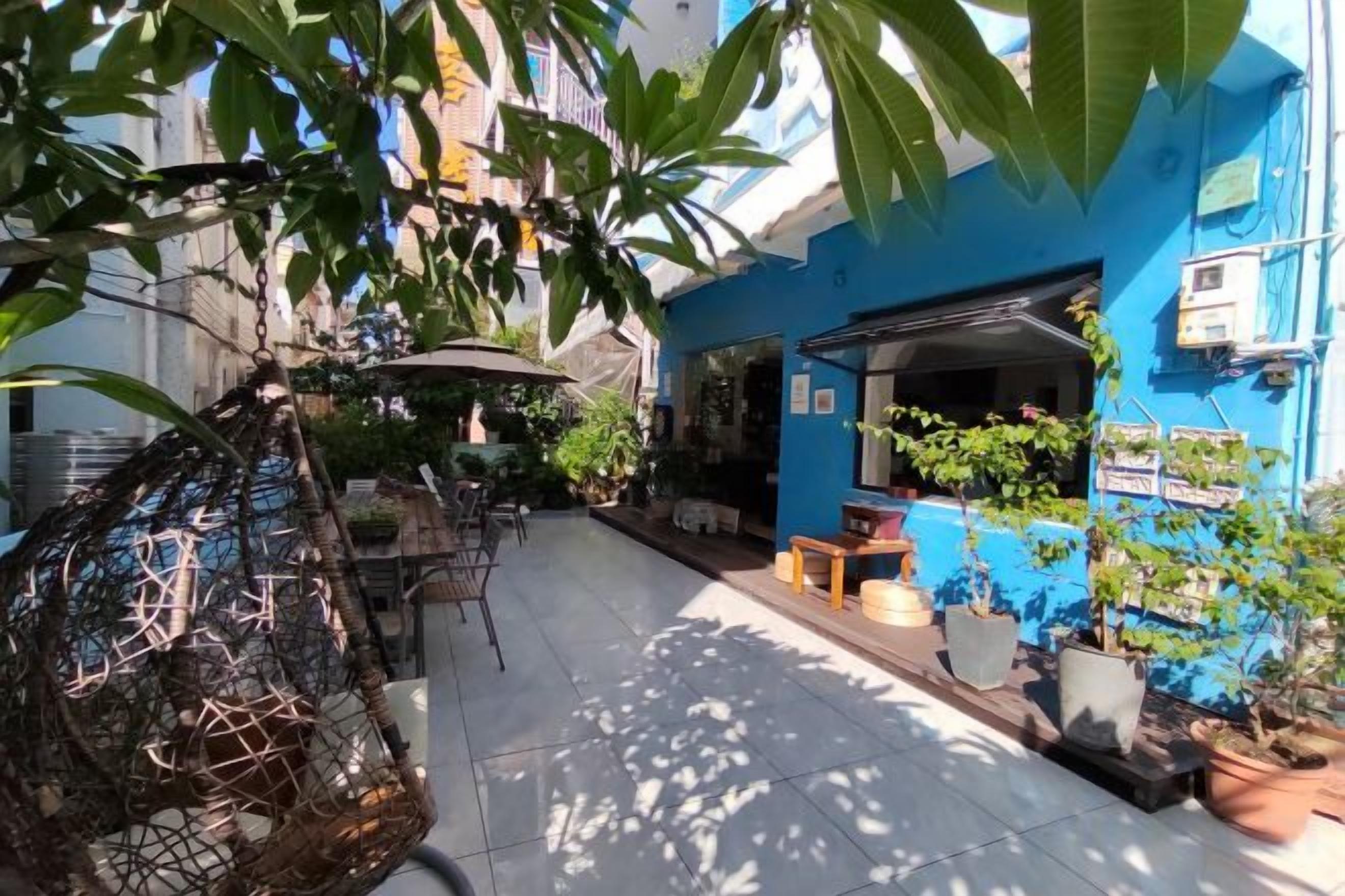 A courtyard with a blue building, outdoor seating, and potted plants.