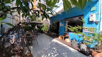 A courtyard with a blue building, outdoor seating, and potted plants.
