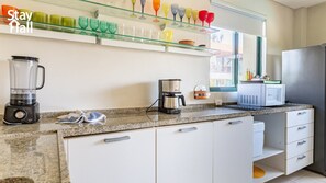 Una cocina moderna con encimera de granito, licuadora, cafetera y microondas.