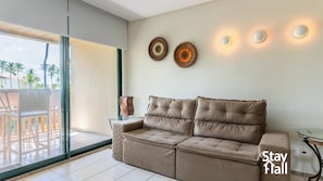 A modern living room with a beige sofa, a glass coffee table, and a decorative wall piece.