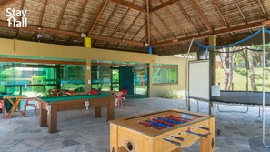 Un área recreativa interior con mesa de fútbol, mesa de billar y trampolín.