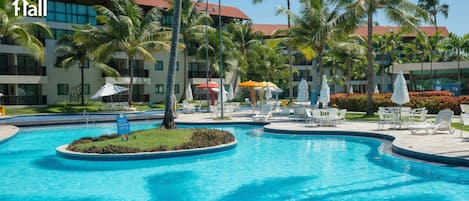 Área de piscina de resort com palmeiras, espreguiçadeiras e guarda-sóis.