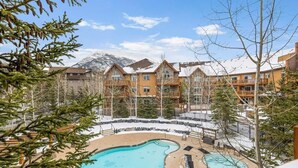 Un resort con piscina, terreno cubierto de nieve y vistas a la montaña.