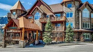 Un gran lodge de varios pisos con fachada de piedra, varios balcones y una entrada destacada con porche cubierto.