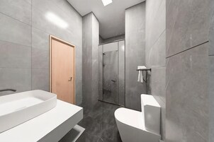 Un baño moderno con un lavabo grande de color blanco, un inodoro y una zona de ducha.