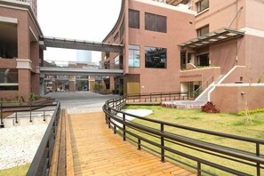 A building with a covered walkway, a grassy area, and a staircase.