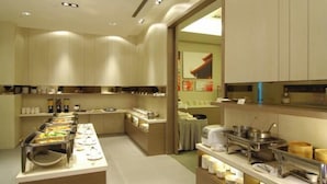 A buffet setup with various food stations and kitchen equipment. - Academy Hotel (Tainan)