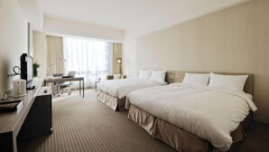 A hotel room with two beds, a desk with a computer, a chair, and a lamp. - Academy Hotel (Tainan)