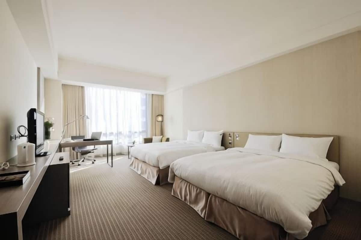 Une chambre dâhĂŽtel avec deux lits, un bureau avec un ordinateur, une chaise et une lampe.