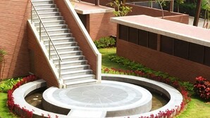 A building with a staircase leading to a circular courtyard surrounded by a brick wall and greenery. - Academy Hotel (Tainan)