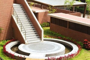 A building with a staircase leading to a circular courtyard surrounded by a brick wall and greenery. - Academy Hotel (Tainan)