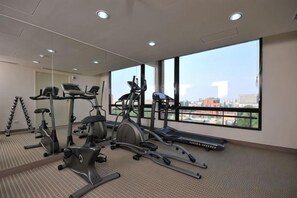 Une salle de sport équipée de matériel d’exercice et dotée de grandes fenêtres.