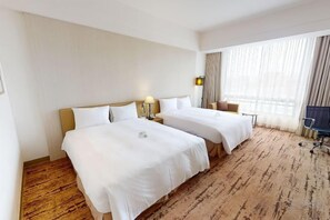 A hotel room with two beds, a desk, a chair, and a large window with curtains. - Academy Hotel (Tainan)