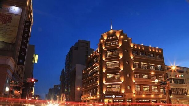A multi-story building with illuminated signage, likely a hotel, featuring a prominent entrance and multiple windows. - Academy Hotel (Tainan)